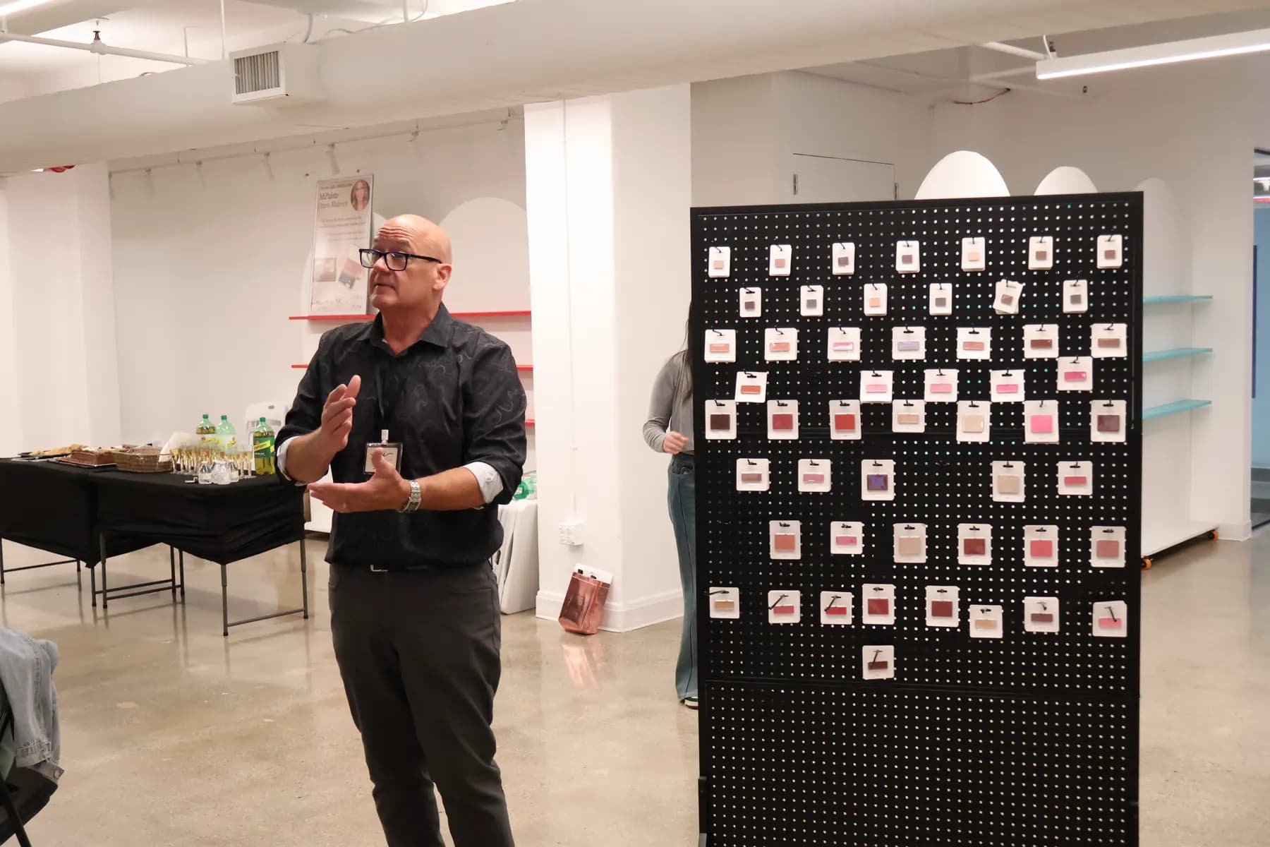 A presenter speaks beside the MiPalette refill shade wall during the brand launch.