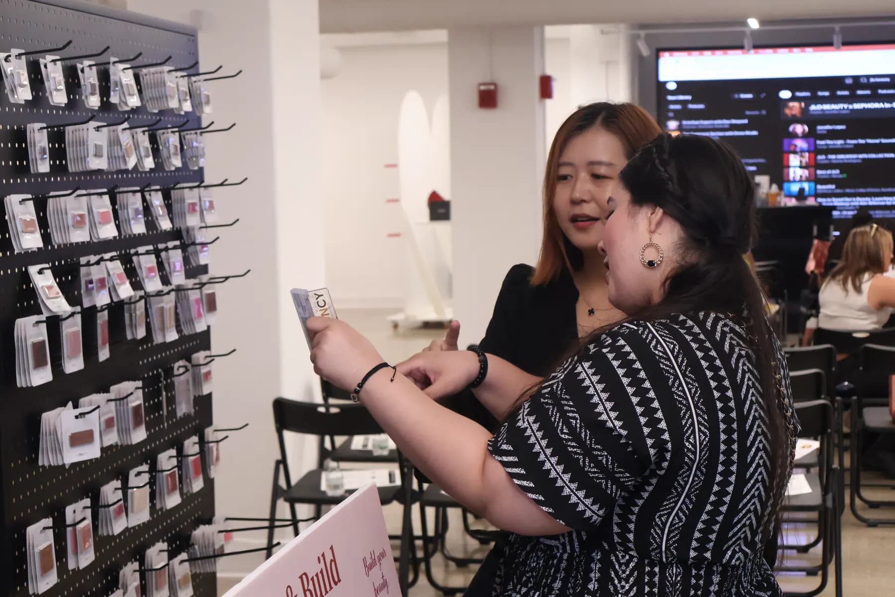 A MiPalette representative helps an attendee compare colors at the refill shade wall.