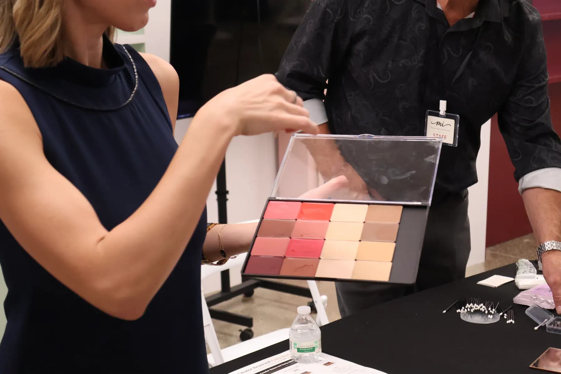 A presenter points to rows of color refills in an open MiPalette demonstration palette.