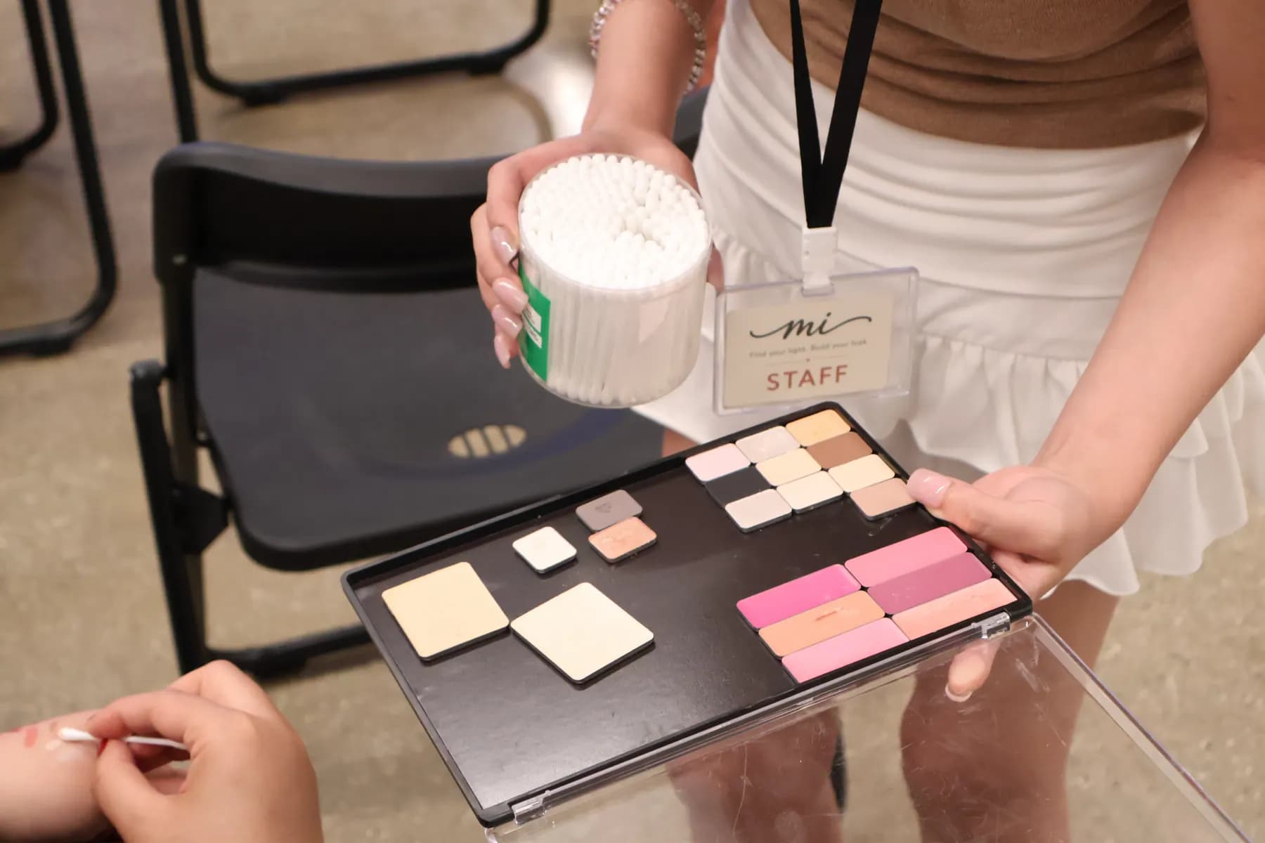 A MiPalette staff member presents neutral, pink, and coral refill pans during a hands-on session.