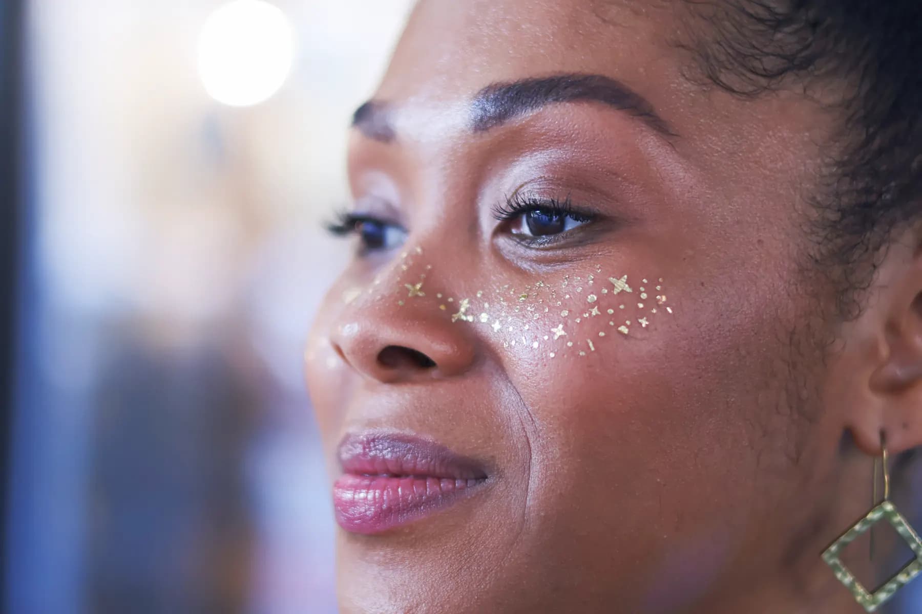 Close-up of a guest's finished makeup look with gold face accents.