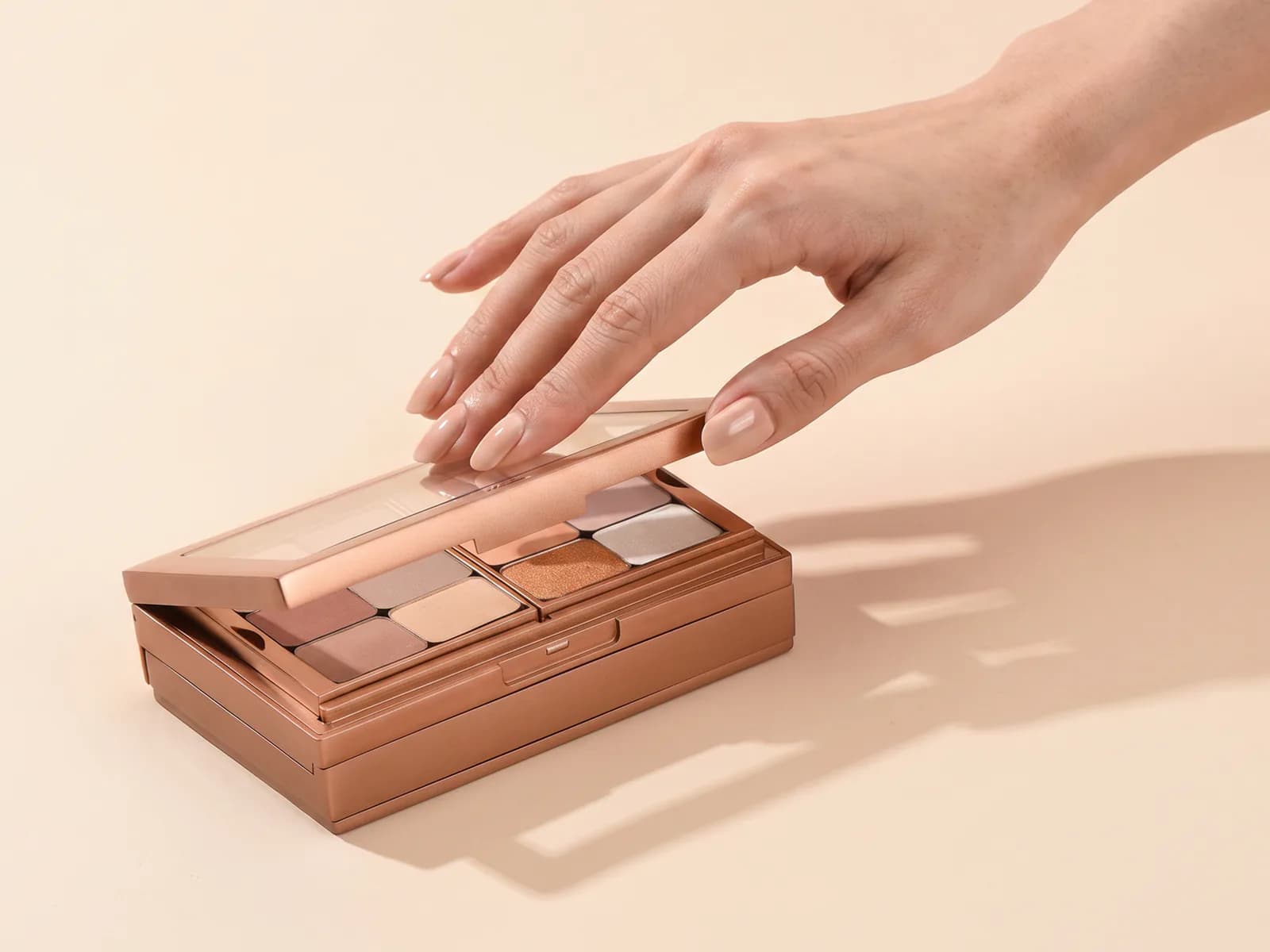 Hand opening an elegant sand-beige metallic makeup case with empty modular slots